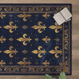 The Midnight Fleur - Washable Rug - JRS017 (Custom Size) in navy blue with gold fleur-de-lis patterns and ornate border rests on a wooden floor, styled with an open book, glasses, and a green plant—ideal for high-traffic areas.