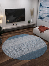 A modern living room features the Bohemian Retreat - Washable Rug - JR1589, ideal for high-traffic areas, with dark wood floors, a wall-mounted TV, a low console with decor, abstract art, and a white ottoman topped by an orange throw blanket.