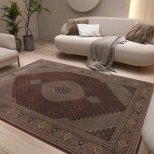 Load image 1 in gallery view. A modern living room with a light sofa, beige cushions, gray throw, green plants, and the Elysian Weave - Washable Rug - JRN1001 featuring a red medallion design on a light wood floor.