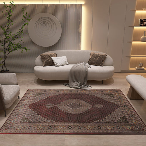 Load image 1 in gallery view. A modern living room features neutral furniture—a curved sofa, armchair, and bench—anchored by the Elysian Weave - Washable Rug - JRN1001 in red. Wall art, minimalist shelves, and a tall plant add cozy elegance to the space.