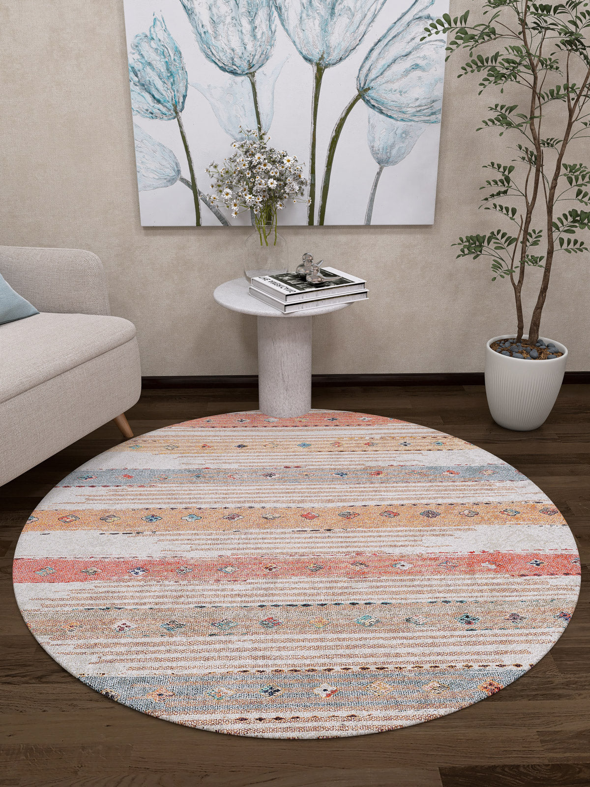 The Nomad's Nostalgia - Washable Rug (JR1669), a round multicolor rug with horizontal stripes, lies on a dark wood floor in a cozy living room with a white armchair, small table, potted plant, and floral wall art. Perfect for high-traffic areas.