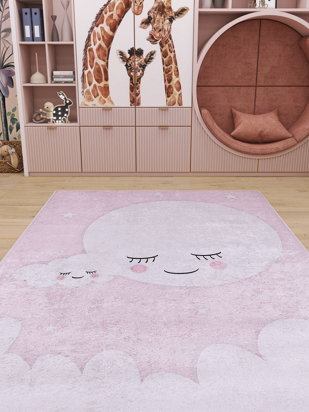 A children’s room with pink shelves, giraffe-illustrated cabinets, a circular pink nook with cushions, and the Cosmic Naptime - Machine-Washable Rug JRC032 in soft pink, decorated with smiling clouds and stars.