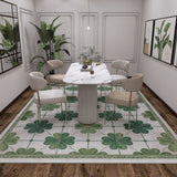 A modern dining room with a marble table, four beige chairs, the Emerald Charm - Washable Rug - JRS013 for high-traffic areas, potted plant, minimal pendant light, and framed art on cream walls over a dark wooden floor.