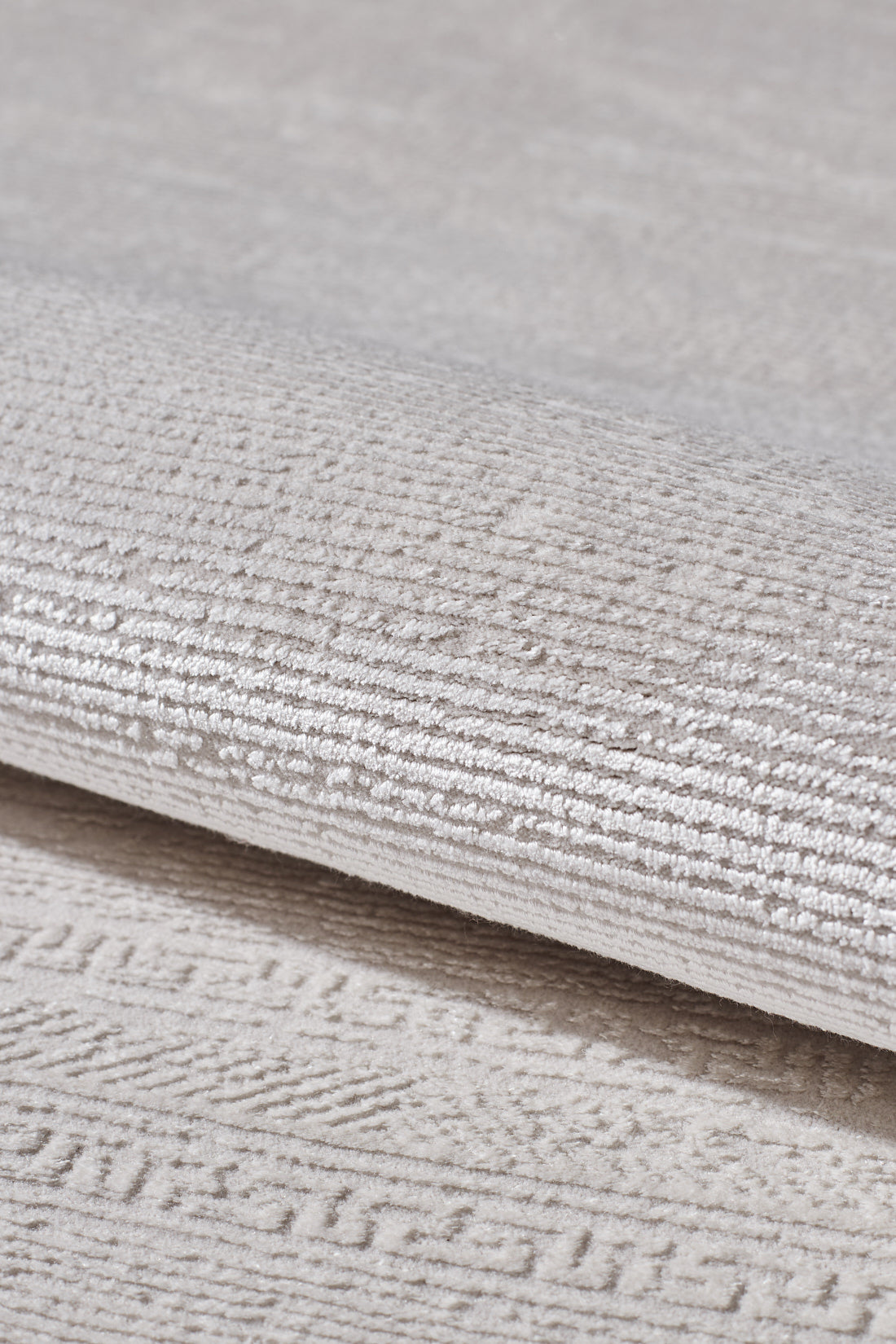 A close-up of the Vanilla Dream Modern Bordered Rug - EW2742 reveals its light beige tone, subtle geometric pattern, and soft velvety surface. The machine-woven details highlight the rug's quality and elegant design.