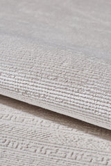 A close-up of the Vanilla Dream Modern Bordered Rug - EW2742 reveals its light beige tone, subtle geometric pattern, and soft velvety surface. The machine-woven details highlight the rug's quality and elegant design.