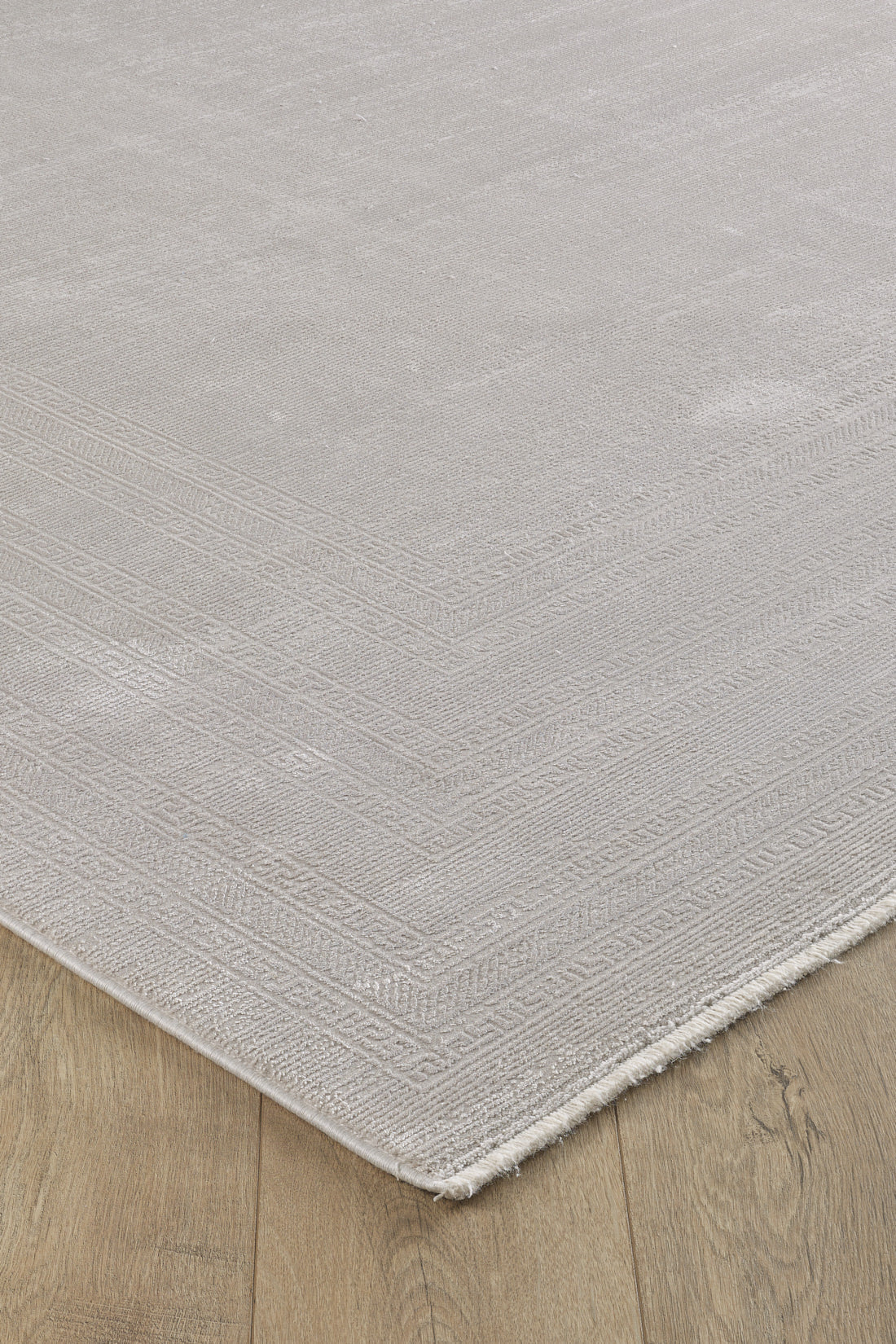 A close-up of the Vanilla Dream Modern Bordered Rug - EW2742 shows its soft, textured surface, subtle geometric border, and neatly finished edges in neutral tones on a light wood floor.