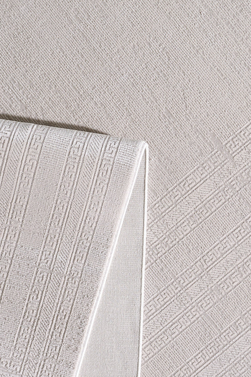 Load image 1 in gallery view. The Vanilla Dream Modern Bordered Rug - EW2742, in folded beige, displays subtle geometric and Greek key motifs atop a matching textured fabric, highlighting its intricate woven details and soft, neutral tones.