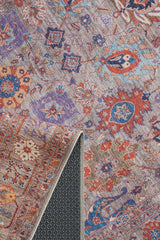 The Velorio Floral Washable Rug - LCC3006 features intricate floral and geometric patterns in red, blue, orange, and purple. A folded corner reveals its textured dark backing, making it ideal for high-traffic areas.