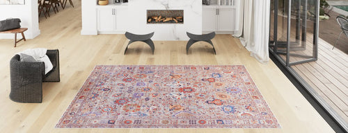 Load image 1 in gallery view. A spacious living room with light wood flooring, the Velorio Floral Washable Rug - LCC3006 in pink and purple for high-traffic areas, modern chairs, a black woven armchair, a white fireplace beneath shelves, and large glass doors opening outside.