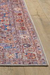 A corner close-up of the Velorio Floral Washable Rug - LCC3006 shows intricate red, blue, and beige motifs on a light wood floor. With a detailed border and textured surface, it's ideal for high-traffic spaces and easily washable.