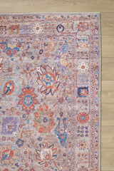 A close-up of the Velorio Floral Washable Rug - LCC3006, featuring intricate red, blue, orange, and beige floral and geometric patterns on a light wood floor—perfect for allergy-sensitive homes or high-traffic areas.