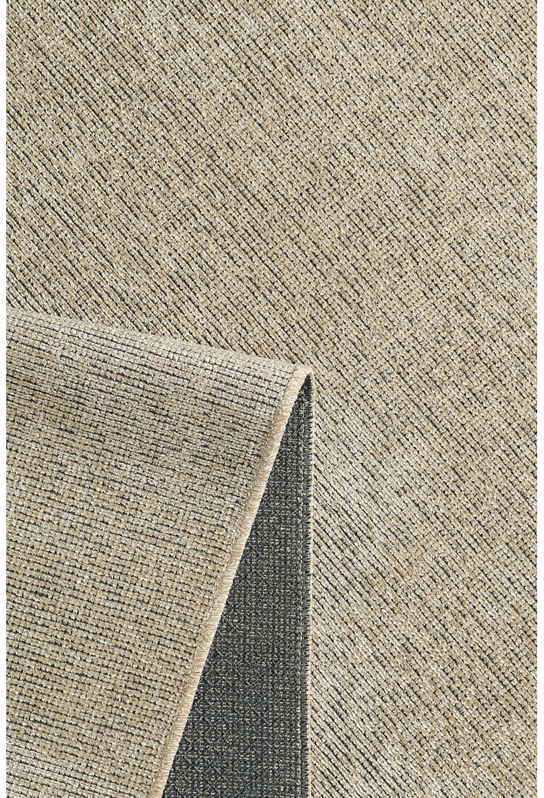 A close-up of the Velvet Touch Beige Area Rug - PST002 shows its textured surface with a subtle grid pattern, and one corner folded to reveal the darker, non-slip backing.