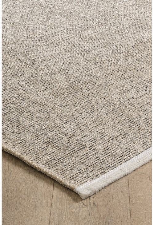 Load image 1 in gallery view. A close-up of the Velvet Touch Beige Area Rug - PST002 shows its rectangular, textured surface with a subtle woven pattern. Placed on a light wood floor, this contemporary rug features a slightly raised edge with a white border on one side.