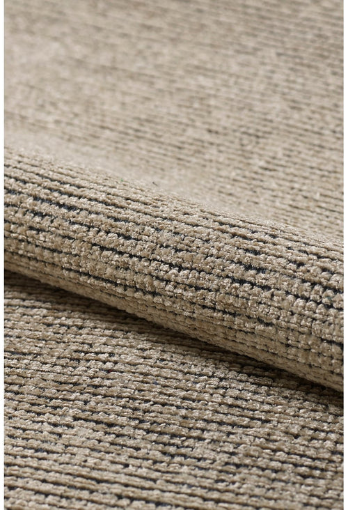 Load image 1 in gallery view. Close-up of the Velvet Touch Beige Area Rug - PST002, featuring a textured beige surface with subtle dark speckles and a soft fold that highlights its contemporary style.