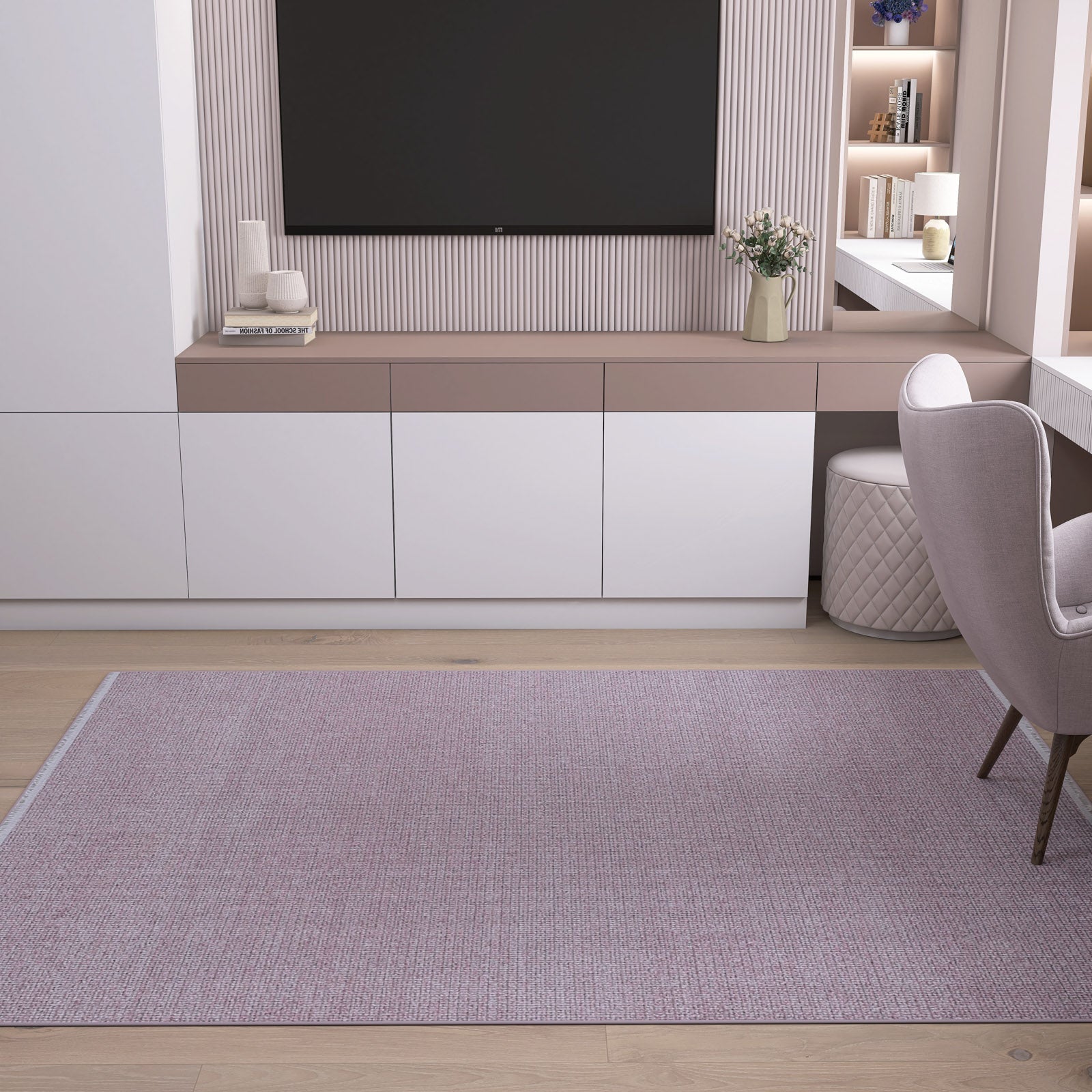 A modern living space with a large wall-mounted TV, minimalist white cabinets, the Velvet Touch Pink Area Rug - PST004, a desk with a light gray quilted chair, and decor like a vase with flowers.