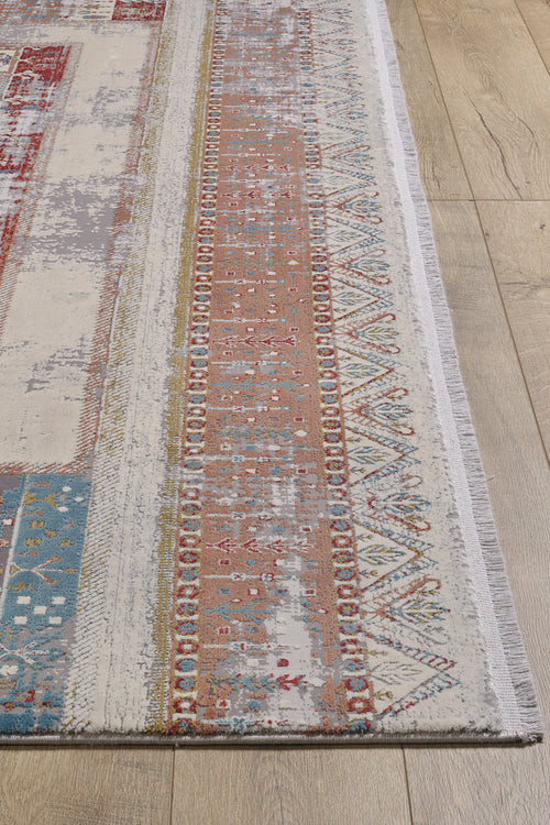 Load image 1 in gallery view. The Vibrant Nomadica Premium Rug - M366C, a machine-made area rug with geometric and traditional motifs in red, blue, yellow, and white, features visible fringe on one side and lies on a light wooden floor.