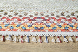 A close-up of the Vibrant Rainbow - Machine-Washable Rug - JR5001 (Custom Size), featuring a colorful geometric pattern with red, orange, yellow, blue, and white shades and tassels—ideal for high-traffic areas.