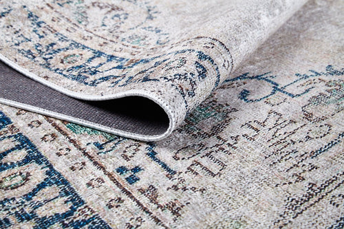 Load image 1 in gallery view. A close-up of the Vintage Beauty - Washable Rug - JR1688 (Custom Size) showcases its intricate blue and beige designs, with a folded corner revealing the underside and texture—ideal for high-traffic areas.