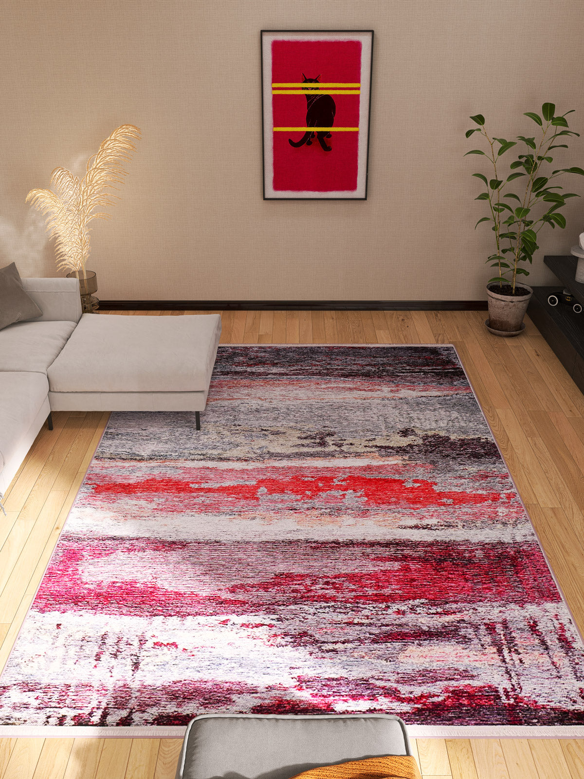 A modern living room features the Vintage Brushed - Washable Rug - JR143 (Custom Size), a white sectional, lush plants, and cat-themed art with bold colors on the beige wall, all atop light wood floors.