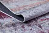 A close-up of the Vintage Brushed - Washable Rug - JR143 (Custom Size), featuring a multicolored flat weave with gray, red, and purple shades, plus a folded corner revealing its black underside and stitched edge.