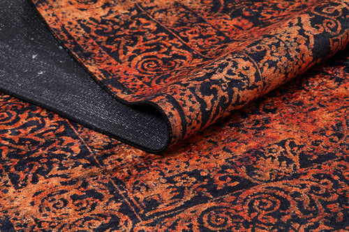 Load image 1 in gallery view. A close-up of the Vintage Glory - Washable Rug - JR1490 (Custom Size) in orange with intricate red and orange patterns on a dark base, featuring a flipped corner that reveals its black underside—ideal for high-traffic spaces.
