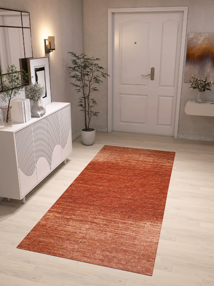 A modern entryway features light wood flooring, the Vintage Reverie - Washable Rug - JRN31 (Custom Size) in red, a white cabinet with decor, wall art, a potted plant, and a closed white door—perfectly arranged for high-traffic areas.