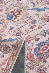 A close-up of the Vivencia Authentic Washable Rug - LCC3016 (Outlet) US in light tones with blue, pink, and beige patterns, showing a flipped corner to reveal its textured, non-slip backing.