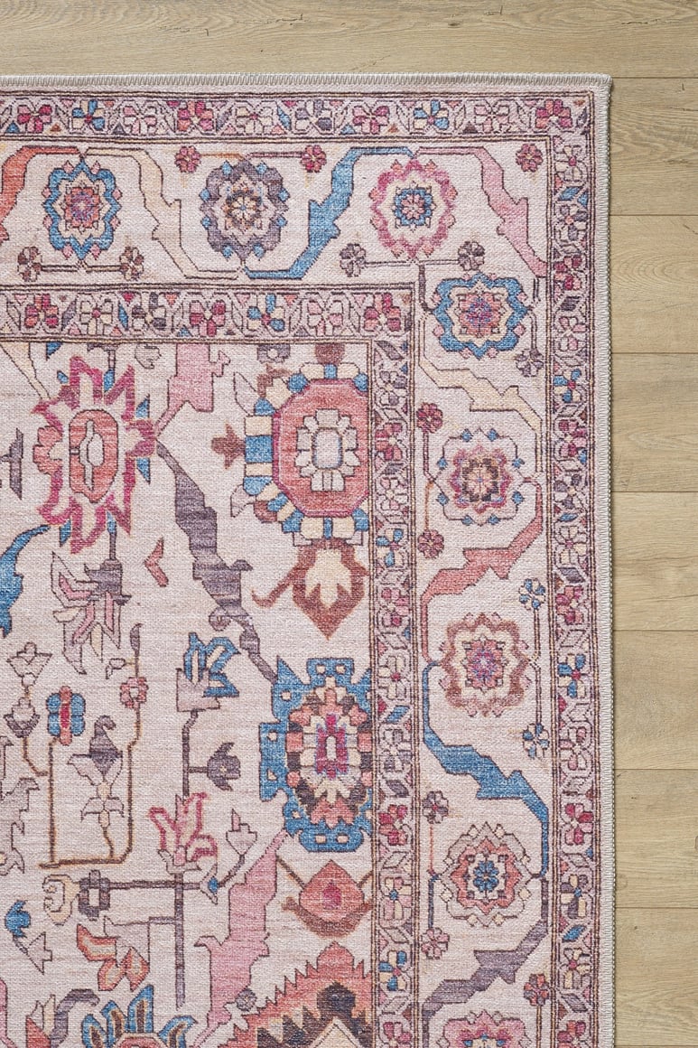 A close-up of the Vivencia Authentic Washable Rug - LCC3016 (Outlet) US, showcasing its durable construction and intricate pink, blue, and beige geometric and floral patterns on a light wooden floor.
