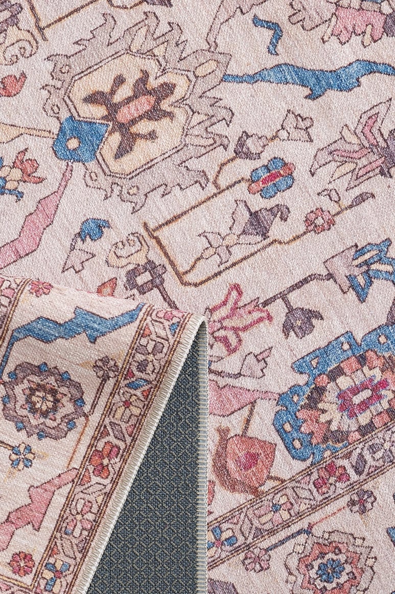 A close-up of the Vivencia Authentic Washable Rug - LCC3016 (Custom Size) shows its pink, blue, and beige floral-geometric patterns. One folded corner reveals the textured non-slip backing—ideal for allergy-sensitive homes.