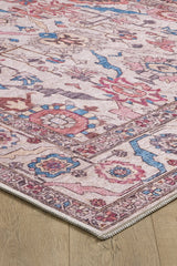 A close-up of the Vivencia Authentic Washable Rug - LCC3016 (Custom Size), featuring an intricate geometric and floral pattern in pink, blue, and beige—perfect for allergy-sensitive homes. Its cream/beige corner is displayed on a wooden floor.