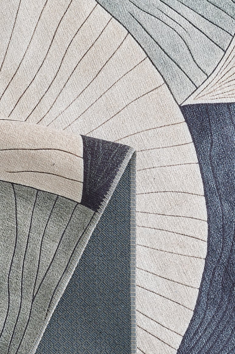 A close-up of the Vivian Modern Washable Area Rug - MDJ010 (Custom Size), featuring an abstract blue, beige, and cream pattern with thin lines and curves. A folded corner reveals its textured underside—perfect for high-traffic spaces.