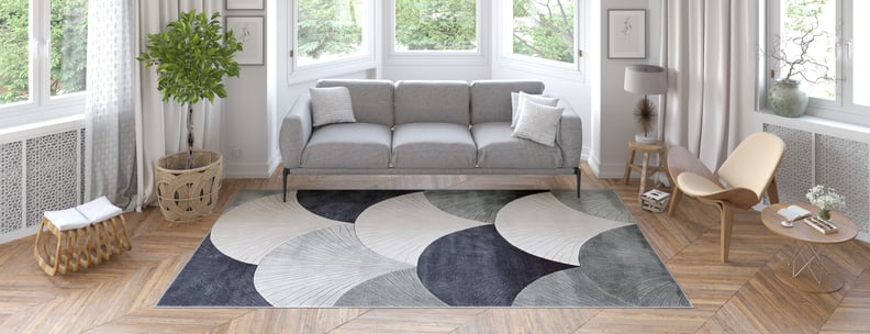 A modern living room featuring the Vivian Modern Washable Area Rug - MDJ010 (Custom Size), paired with a gray sofa, light wood chair, round coffee table, and potted plant—perfect for sunny spaces with parquet floors and high foot traffic.