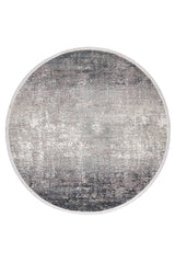 The Vortexia Silver Premium Rug - M472A is a round, machine-made rug with a distressed, textured pattern in gray, white, and black for a modern look in neutral tones.
