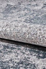 A close-up of the Vortexia Silver Premium Rug - M472A, showcasing its textured surface in gray, white, and dark blue with an abstract mottled design and subtle distressed details.