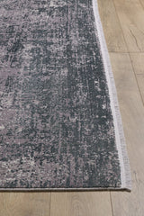 A close-up of the Vortexia Silver Premium Rug - M472A, showcasing its pixelated gray and lavender pattern on a light wood floor. The machine-made rug features a thin, light-colored border for a modern touch.