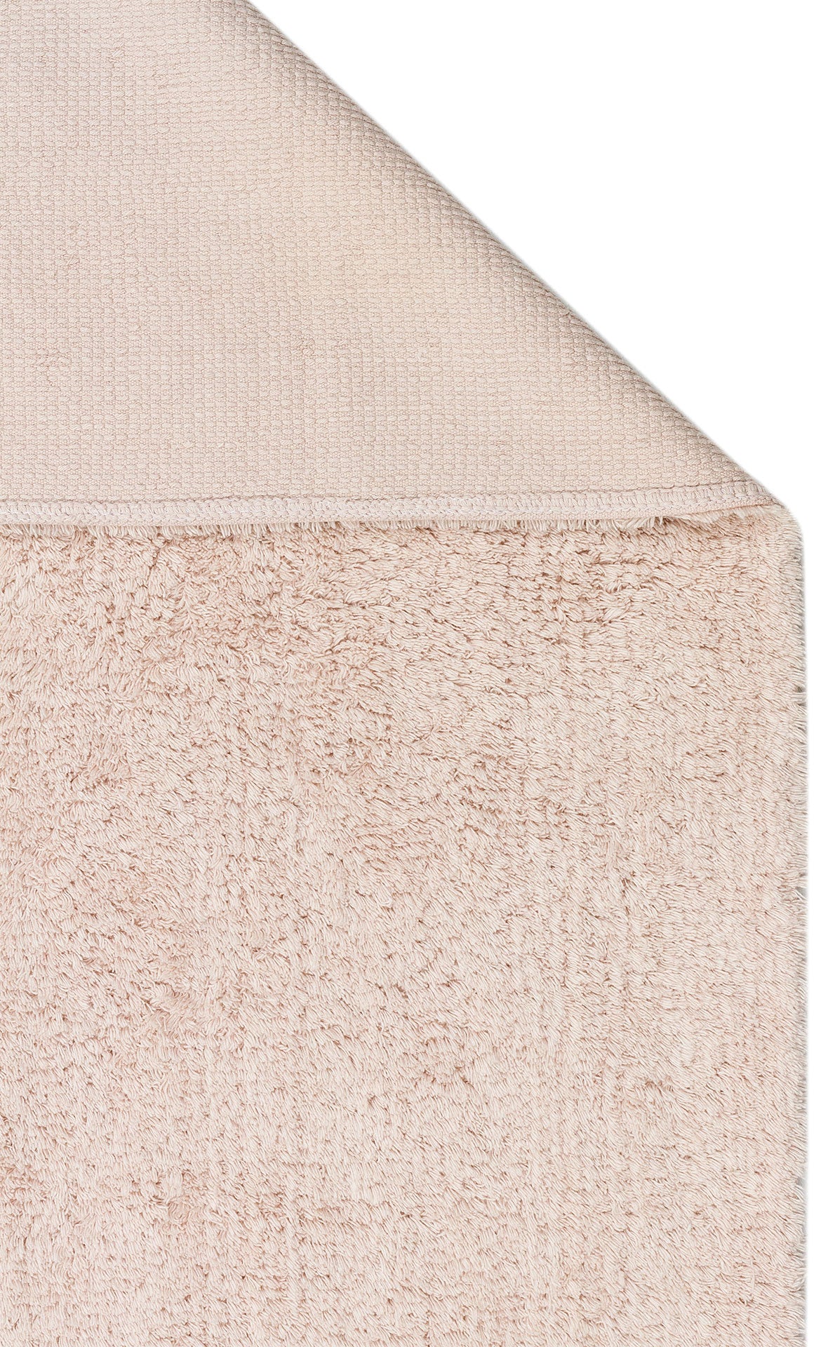 A close-up of the Warm Sand - Washable Shaggy - CBNPLAIN shows its soft, textured fabric and neatly finished edge, evoking the plush comfort and elegance of a high-quality shaggy rug in a warm beige tone.