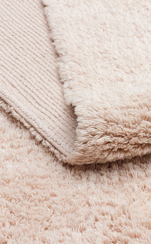 Load image 1 in gallery view. A close-up of the Warm Sand - Washable Shaggy - CBNPLAIN rug shows its plush cream-beige surface and textured underside—ideal as a cozy, washable accent for any space.