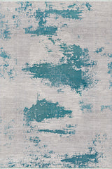 The Whispering Mist Modern Rug - Blue - HRD001 features a machine-made, abstract distressed pattern with large teal blue patches on a light gray background for a textured, contemporary look.