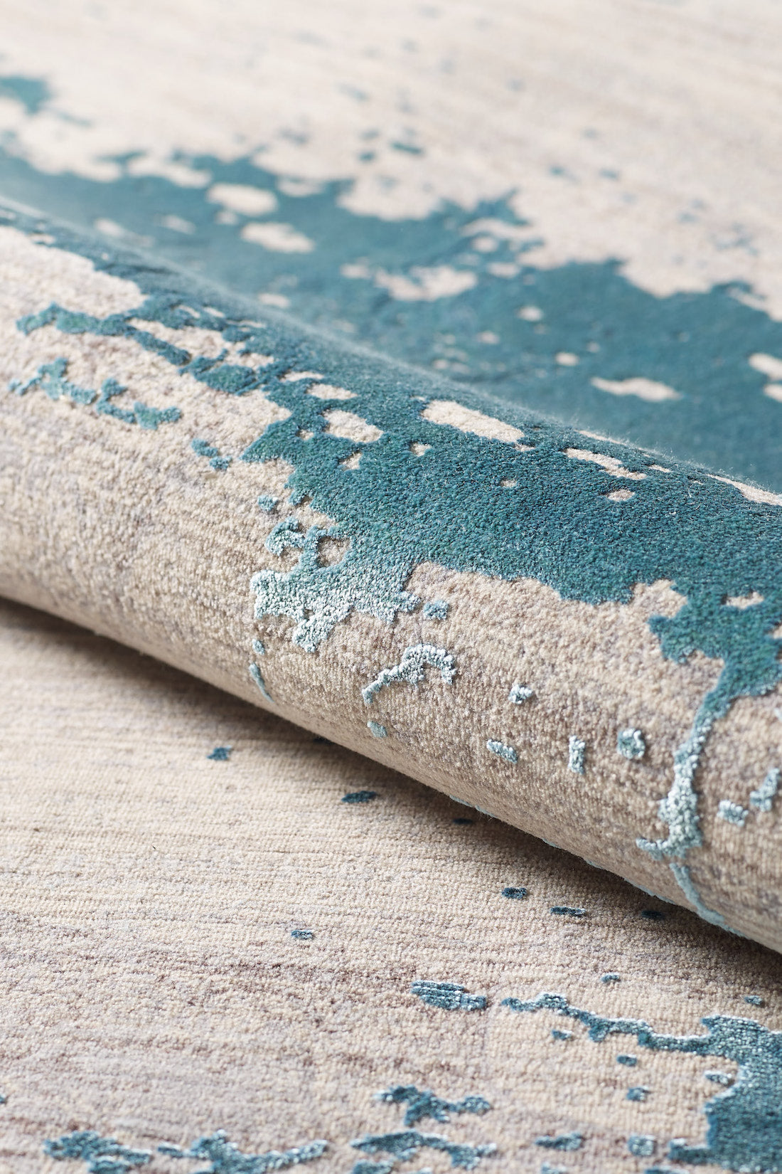 A close-up of the Whispering Mist Modern Rug (Blue - HRD001) shows its machine-made beige base with textured teal abstract splashes, creating a stylish and artistic modern pattern.