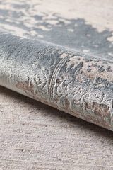 A close-up of the Whispering Mist Modern Rug - Silver - HRD002 highlights its machine-made, rolled edge with intricate gray, beige, and cream patterns plus a soft, plush surface for a modern distressed look.