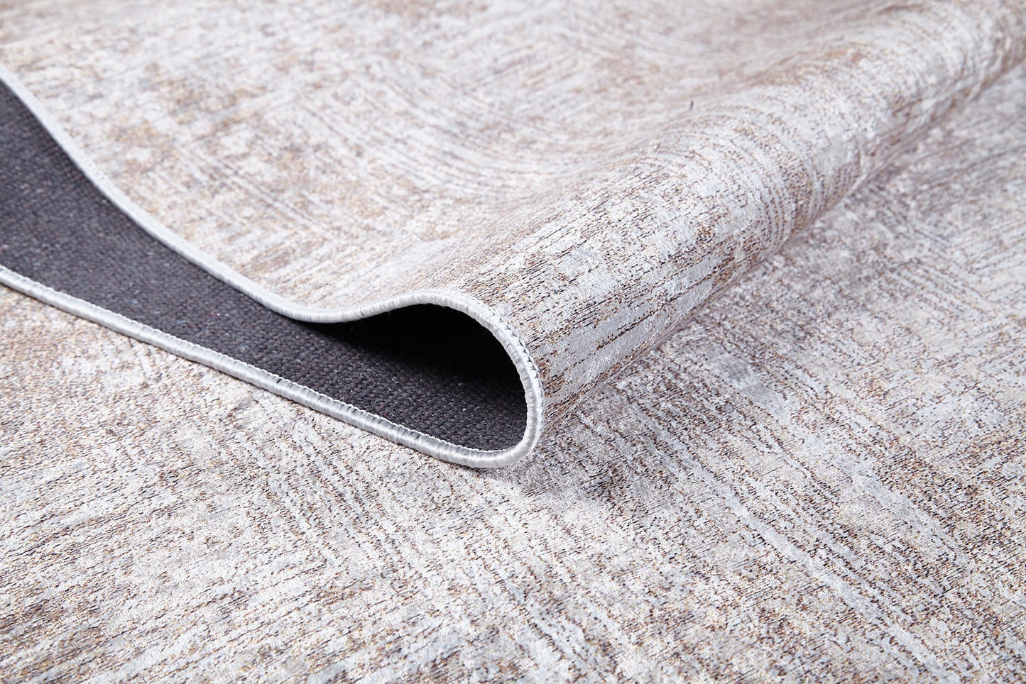 A close-up of the Wildflower Fields - Washable Rug - JR1632 (Custom Size) in cream and beige, with one corner folded to show its dark non-slip backing. The washable rug displays a subtle, abstract pattern.