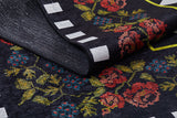 A close-up of the Wildflower Wonderland - Washable Rug - JR587 (Custom Size) shows a folded black corner with a floral pattern in red, pink, and blue flowers, green leaves, and white rectangles—perfect for high-traffic areas.