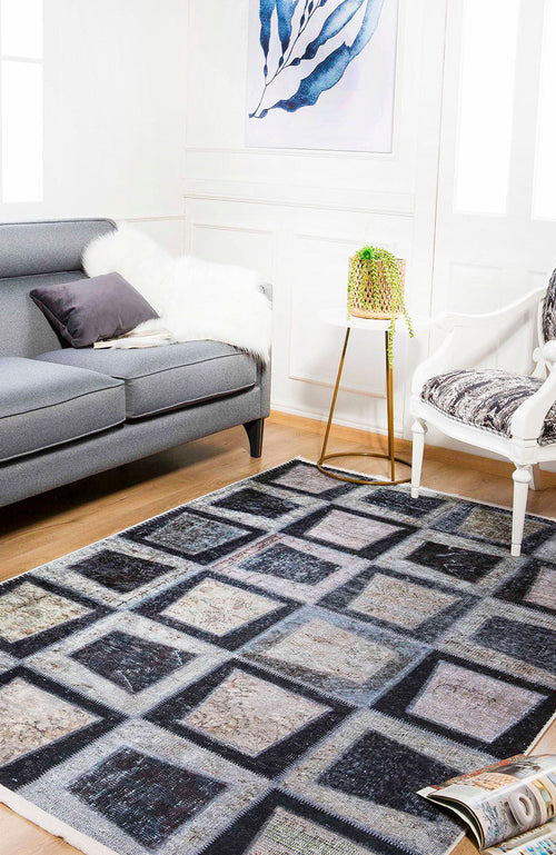 Load image 1 in gallery view. A modern living room with a gray sofa, white armchair, Windowpane Wonder - Washable Rug - JR184 (Custom Size) ideal for high-traffic areas, small side table with a plant, fur throw, framed leaf artwork, and an open magazine on the floor.