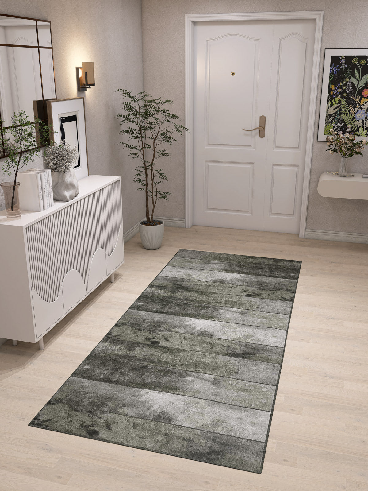 A modern entryway with light wood floors, a Wistful Pattern - Washable Rug - JRN35 (Custom Size) in gray-green, white door, potted plant, white console table with decor, wall sconce, and floral artwork on the wall.
