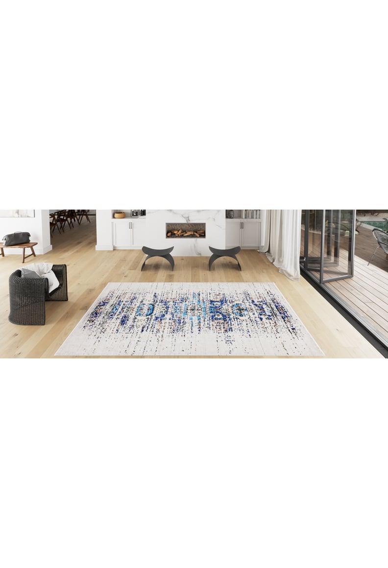 Modern living room with light wooden floors, black armchairs, fireplace, and floor-to-ceiling windows to the patio. The Worn-Out Abstract - Washable Rug - JR339 features blue and white patterns, perfect for allergy-sensitive or busy areas.