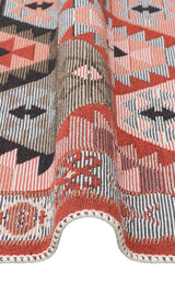 A close-up of the Woven Spirit - Washable Double-Sided Kilims - AR42 shows detailed geometric patterns in red, black, beige, and cream with rich texture and a softly curved edge.