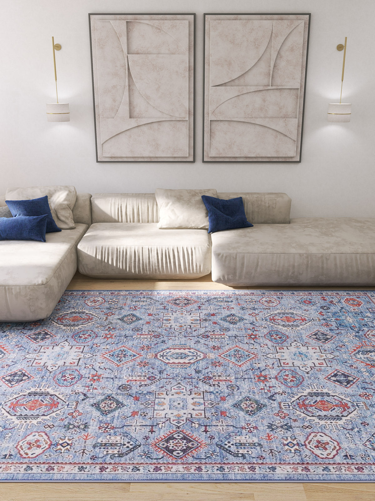 A modern living room featuring a cream sectional sofa, blue accent pillows, two abstract beige wall art pieces, wall-mounted lights, and the Xanadu Handmade-Design Blue Washable Rug - LCC3013 (Custom Size).