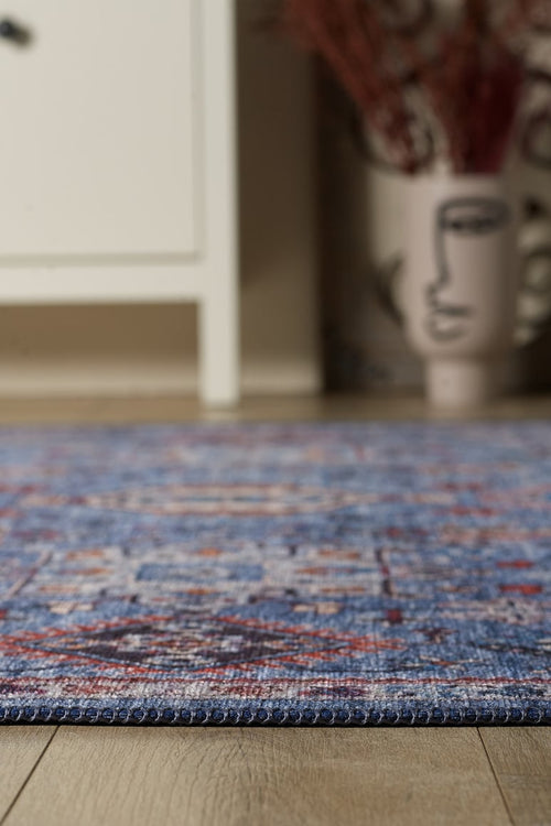 Bild 1 in Galerieansicht laden. Close-up of the Xanadu Handmade-Design Blue Washable Rug - LCC3013 (Custom Size) with a flat weave on a wooden floor; in the background, a white cabinet and an abstract-face vase with dried branches.