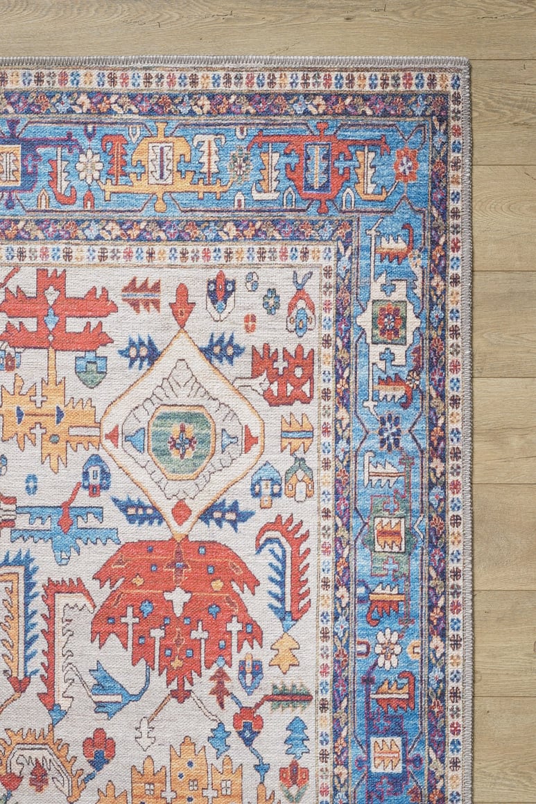 The Yonder Blue Cream Washable Rug - LCC3045 showcases vibrant multicolor patterns in red, blue, yellow, and white on a light wooden floor. With symmetrical motifs and ornate borders, it's perfect for high-traffic areas and adds a stylish touch.