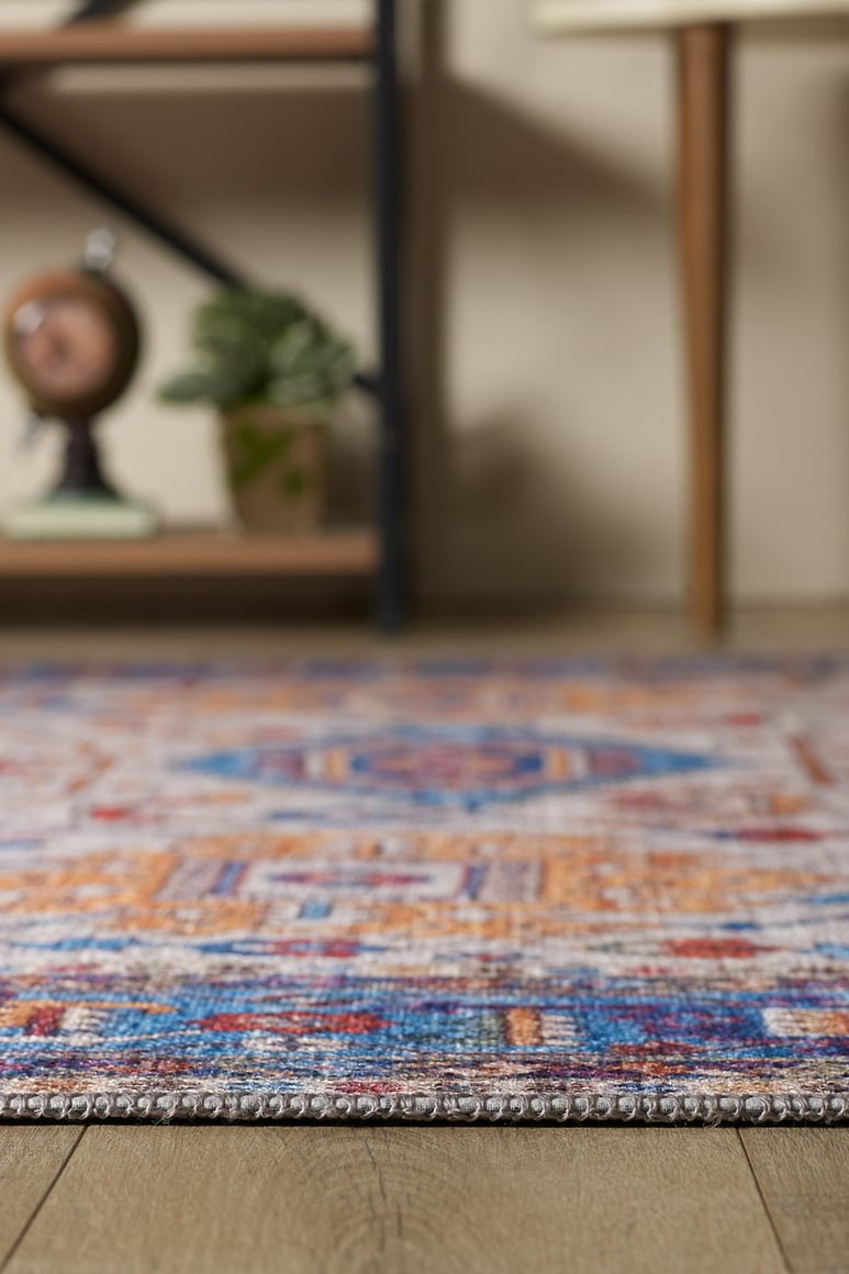 A close-up of the Yonder Blue Cream Washable Rug - LCC3045 on a wooden floor, with blurred shelves, a plant, and a small globe in the background—ideal for adding style to high-traffic spaces.